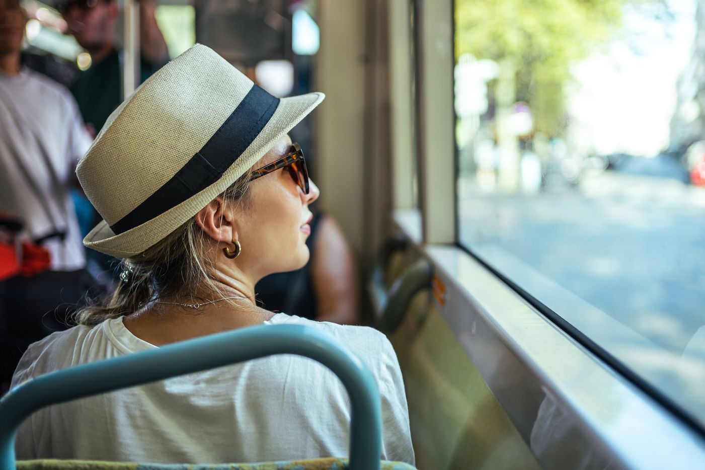 Relaxed female traveler riding a shuttle bus during the day, enjoying a scenic view through the window on her way to a hotel near airport.
