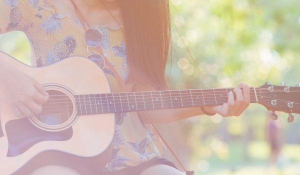 Woman hand is playing acoustic guitar in the garden